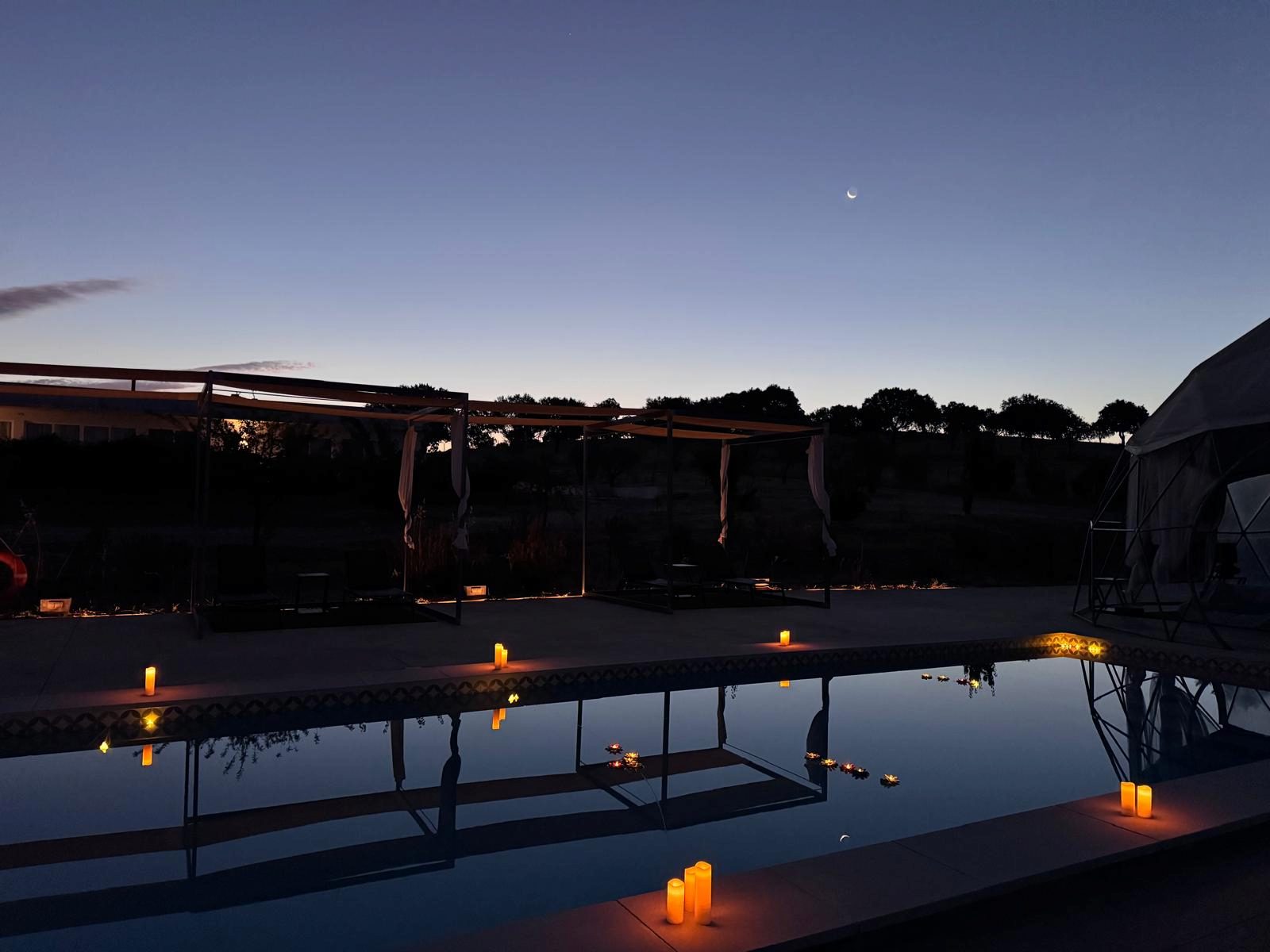 Marriage proposal setup by the candlelit pool at Glamping Skies, at dusk in the Alentejo
