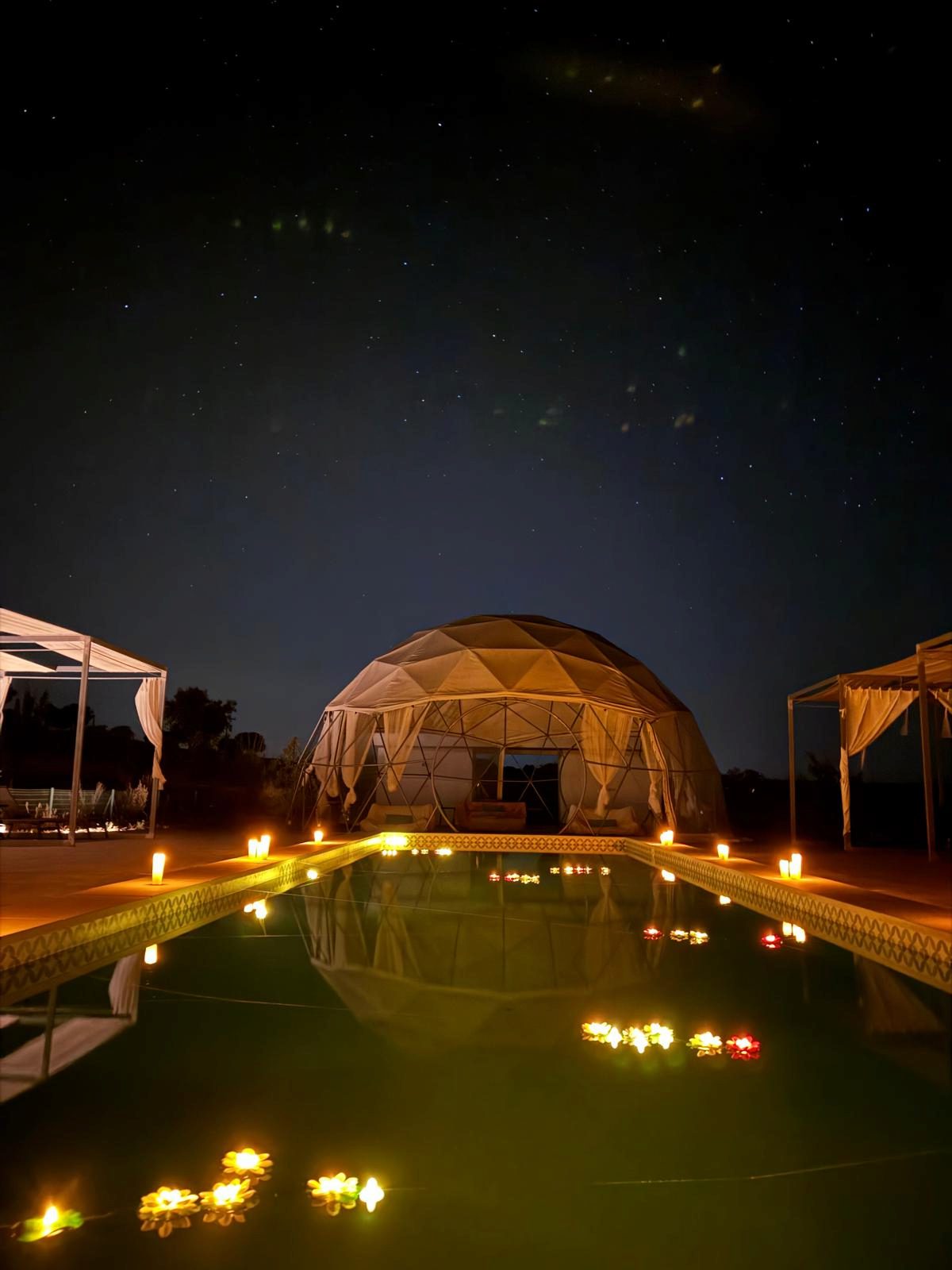 Candles surrounding the pool and floating flowers for a starlit marriage proposal
